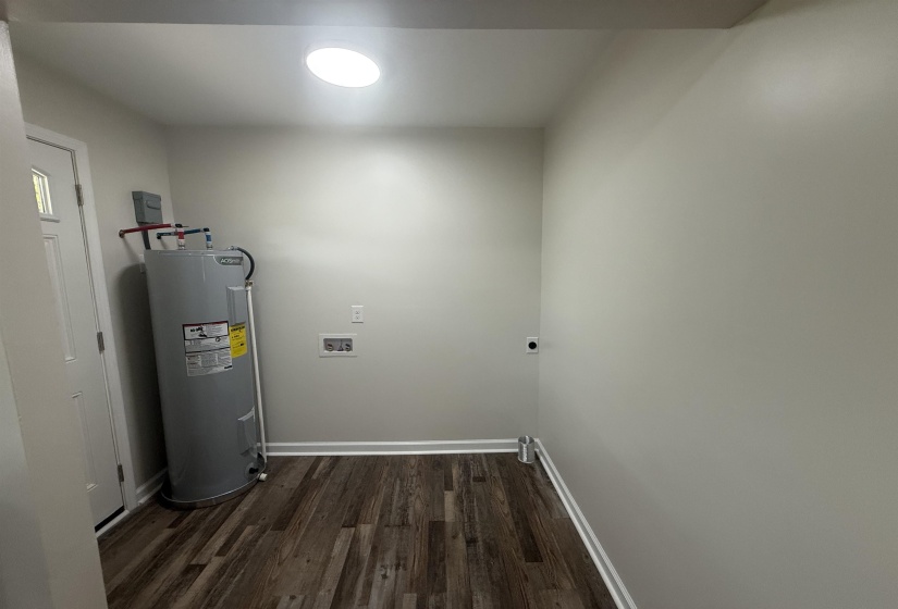 Utility room with wood-finish flooring and a contemporary overhead light fixture