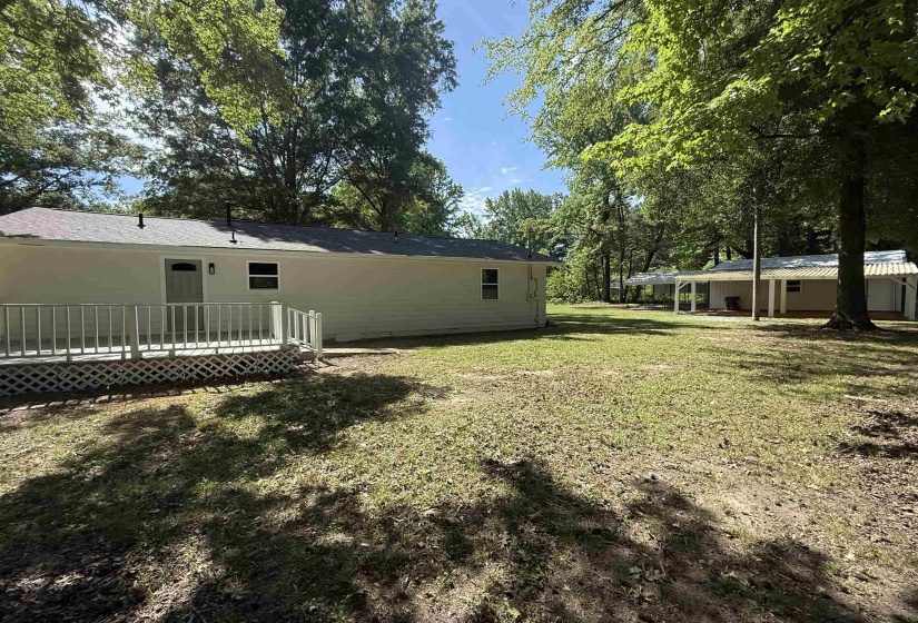 Rear exterior of the property featuring a deck with white railings, a light-colored exterior finish, and a gray shingled roof