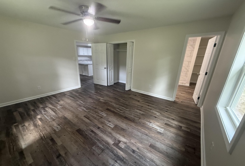 Spacious room featuring wood-finish flooring, light neutral walls, and a ceiling fan with integrated lighting