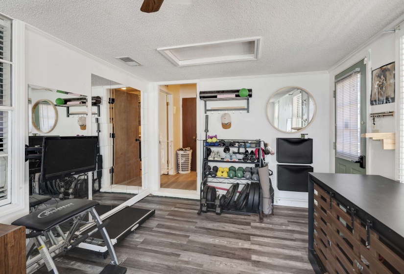 Spacious room featuring wood-finish flooring, white walls, and a ceiling fan