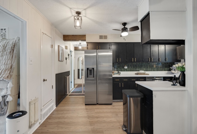 Kitchen featuring black cabinetry, white countertops, and an iridescent subway tile backsplash