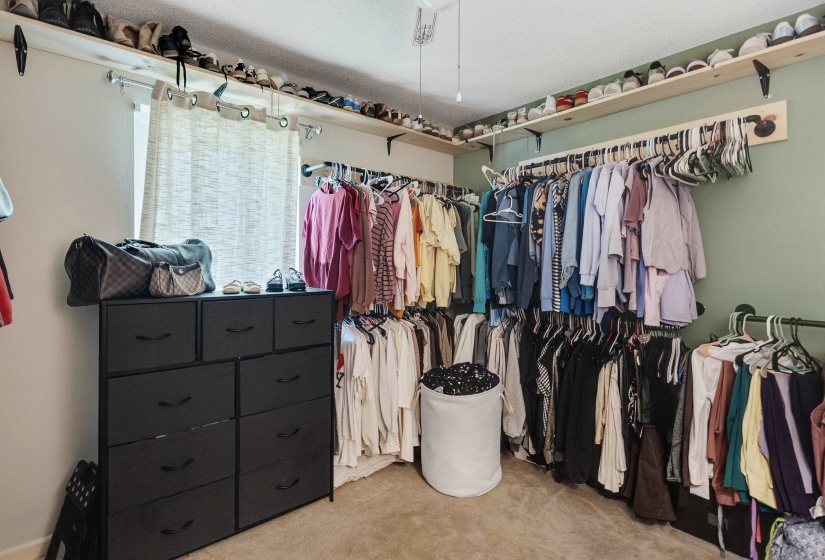 Spacious walk-in closet featuring extensive wall-mounted shelving and multiple clothing rods for organization