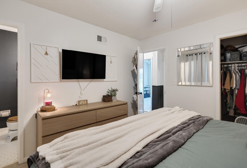 Bedroom featuring a wood-finish dresser and an open closet with built-in shelving and hanging rods