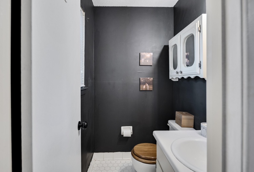Powder room with dark wall paint and white hexagonal floor tiles