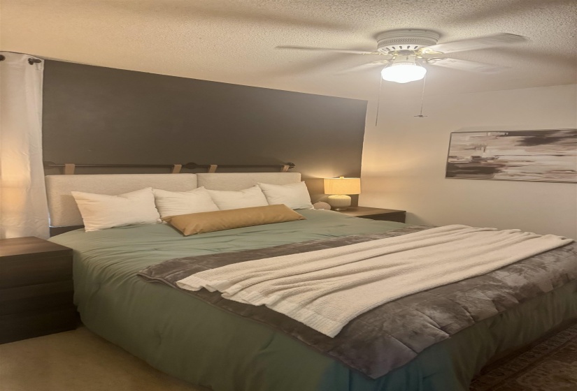 Bedroom featuring a dark accent wall, ceiling fan with integrated lighting, and carpet flooring