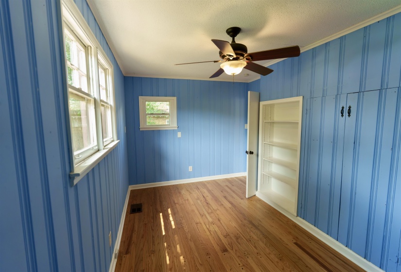 Room featuring vertical paneling, wood-finish flooring, and multiple windows