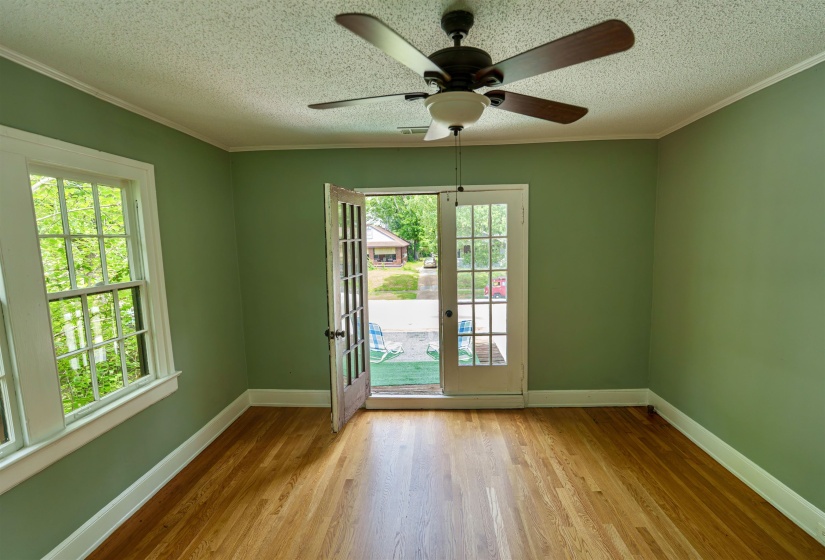 Spacious room featuring wood-finish flooring, a multi-pane window, and a ceiling fan