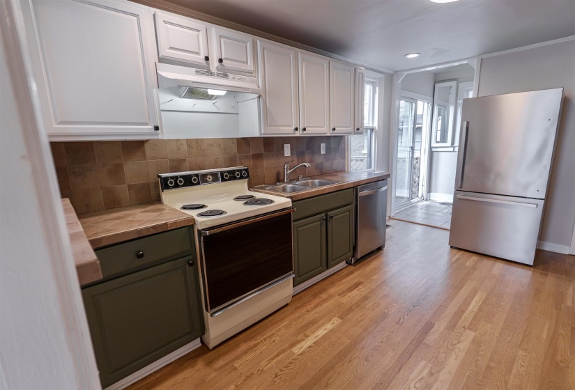 Kitchen featuring wood-finish flooring, white upper cabinetry, and contrasting green lower cabinetry