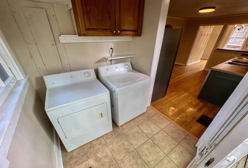 Laundry area featuring tile flooring, wood cabinetry, and a window