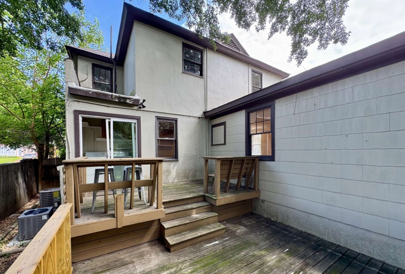 Spacious multi-level deck with wooden railings, steps, and direct access to interior via sliding glass doors