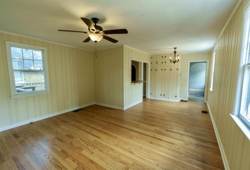 Spacious interior room featuring wood-finish flooring and light-toned vertical paneling