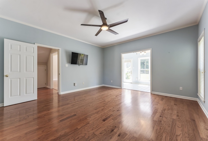 Spacious primary bedroom featuring wood-finish flooring, light blue walls, and a vaulted ceiling