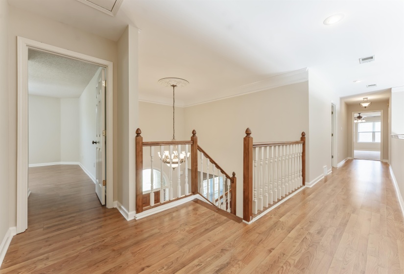 Upper level landing featuring wood-finish flooring, white baseboards, and crown molding