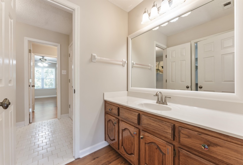 Bathroom vanity featuring a single basin sink, white countertop, and wood-finish cabinetry