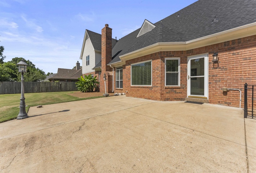 Expansive concrete patio area with a brick exterior, multiple windows, and a glass-paneled exterior door