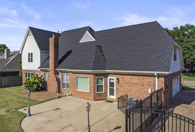 Expansive paved patio area featuring a brick exterior, gabled rooflines, and a two-car garage