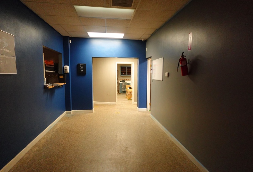 Corridor featuring a paneled ceiling and carpet floors