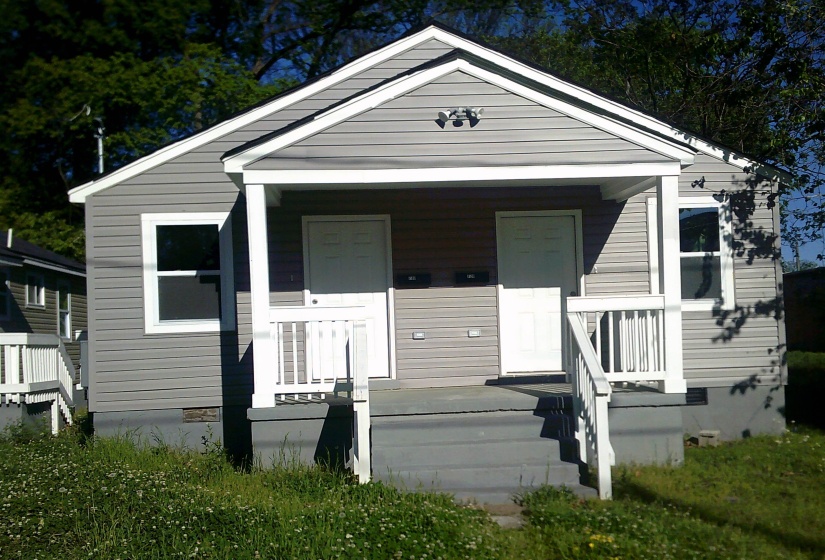 Two-unit property featuring gray horizontal siding and a shared front porch with white railing