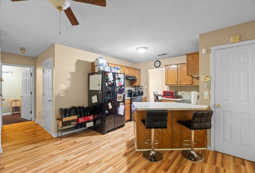 Kitchen featuring wood-finish flooring, wood cabinetry, and an eat-at peninsula with a light-toned countertop