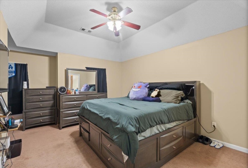 Recessed ceiling with a central fan light fixture, light beige wall color, and carpeted flooring