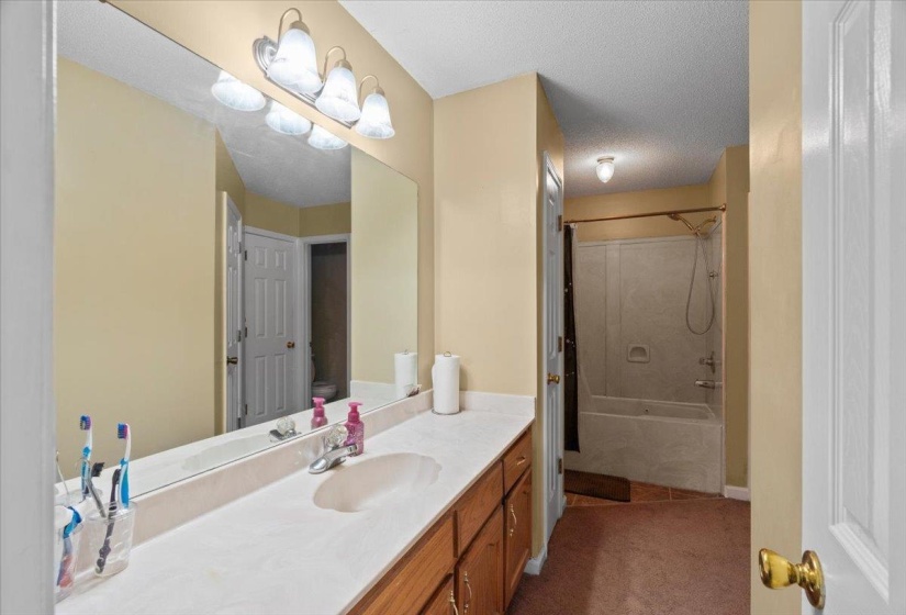 Bathroom featuring an extended vanity with an integrated sink, polished chrome faucet, under-cabinet storage, and a full-width mirror