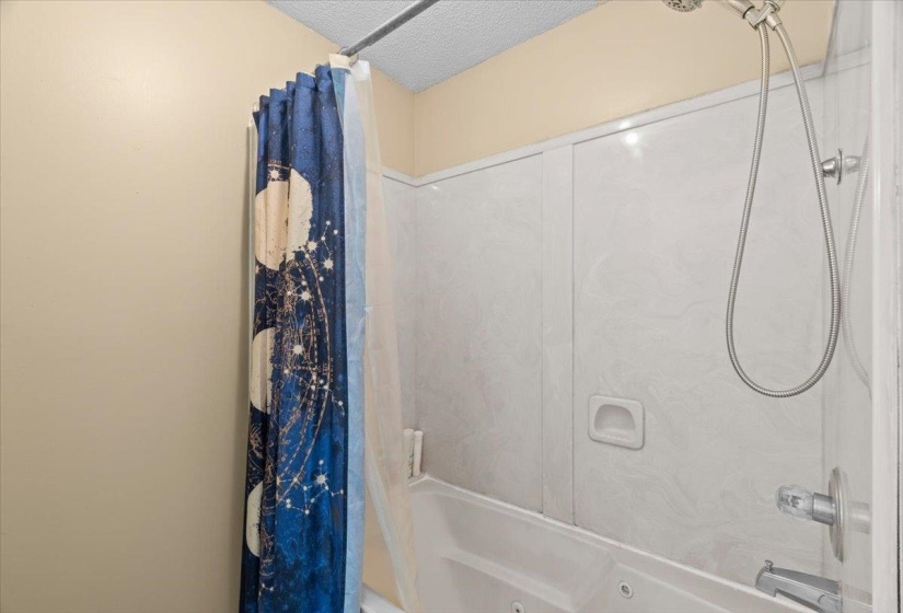 Tub and shower combination featuring a brushed nickel showerhead and faucet