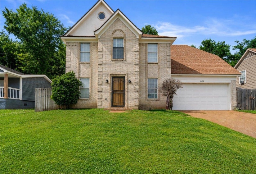 Two-story brick facade residence with an attached two-car garage, prominent gabled roofline, and an arched entry above the front door