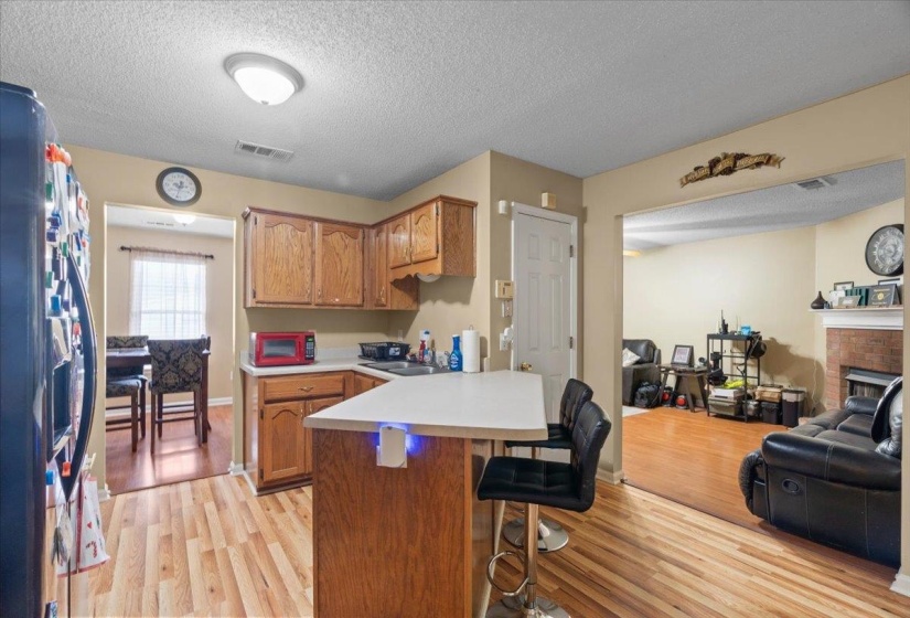 Kitchen featuring wood-finish flooring, light wood cabinetry, light countertops, and a breakfast bar