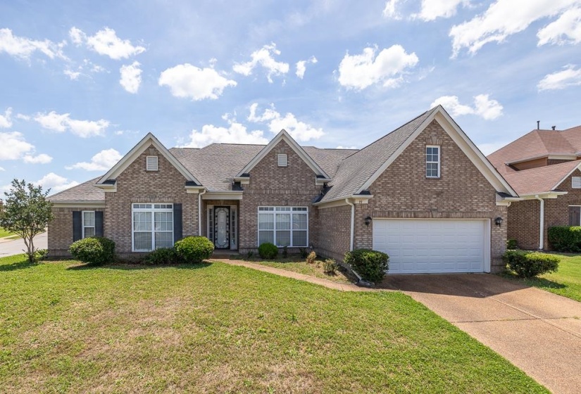 Brick exterior with contrasting dark shutters, a front entry with decorative glass, a two-car garage, and a gabled roofline