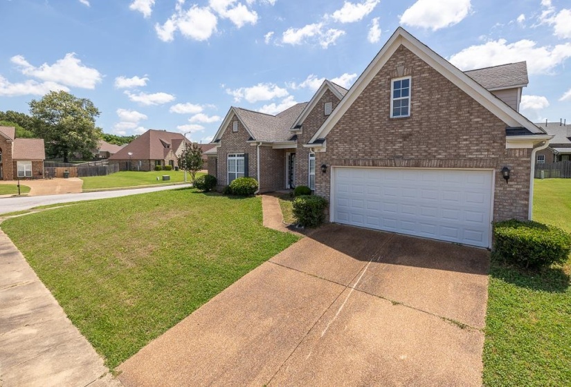 Brick exterior featuring a two-car garage, pitched rooflines, and a concrete driveway