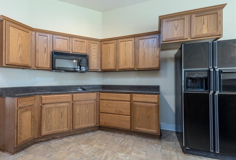 Kitchen featuring extensive wood cabinetry, dark speckled countertops, and an integrated microwave