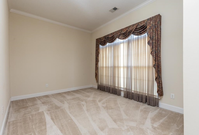 Spacious room featuring neutral carpeting, light-toned wall paint, and white crown molding