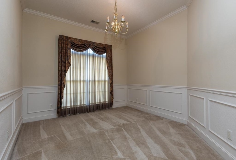 Room featuring a large window, panel molding, crown molding, and a brass chandelier