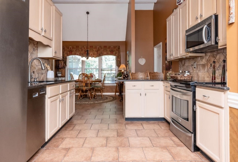 Kitchen with tile flooring, light-toned cabinetry, dark countertops, and stainless steel appliances