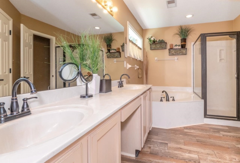 Spacious bathroom featuring a double vanity with integrated sinks, a built-in soaking tub, and a separate glass-enclosed shower