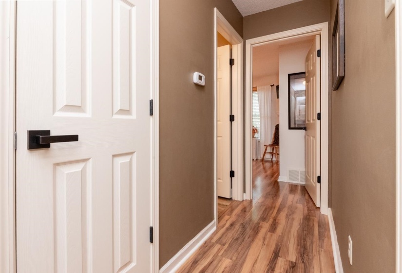 Hallway featuring wood-finish flooring, neutral wall paint, and white trim