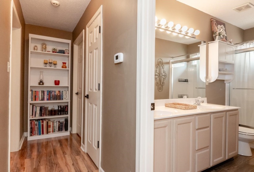 Full bathroom featuring a double vanity with two undermount sinks, a large vanity mirror with strip lighting, a built-in shower with a glass enclosure, and a built-in medicine cabinet