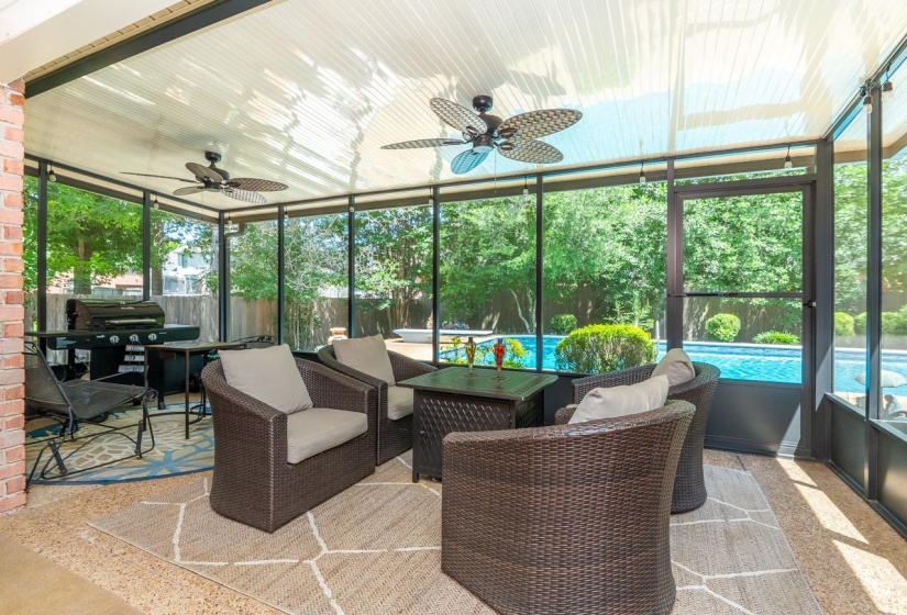 Screened patio featuring a paved stone floor, brick wall accent, and multiple ceiling fans
