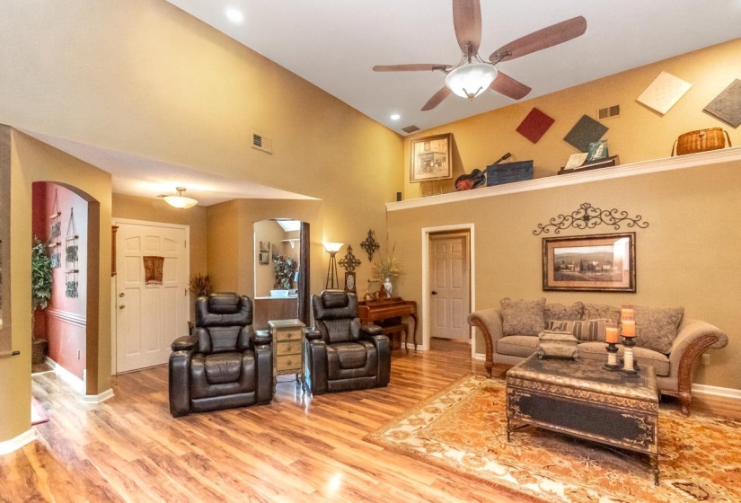 Spacious living area featuring wood-finish flooring, vaulted ceilings, and recessed lighting