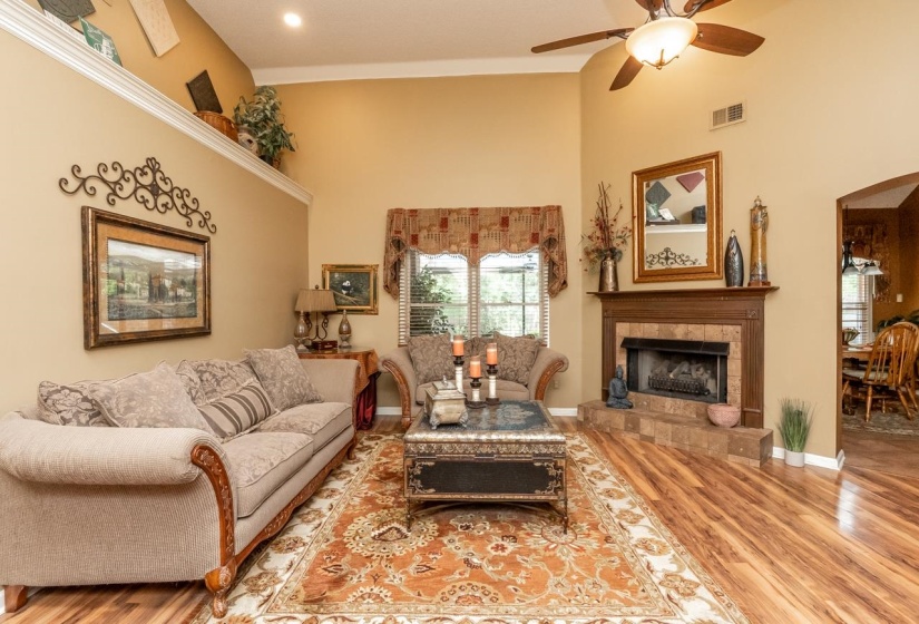Spacious living area featuring high vaulted ceilings, wood-finish flooring, and a fireplace with a tile surround and wood mantel