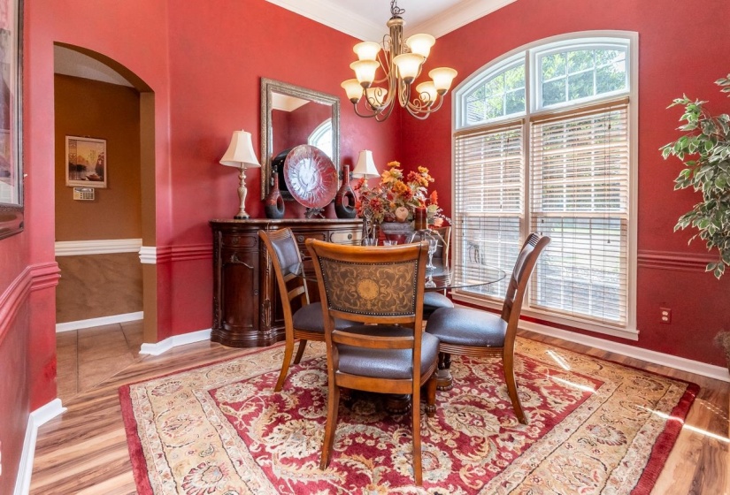 Formal dining area featuring rich wall color, wood-finish flooring, and white crown molding
