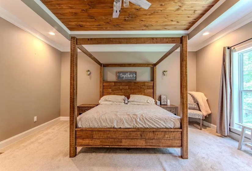 Recessed lighting illuminates a room featuring a wood-panel ceiling, crown molding, and neutral-toned walls