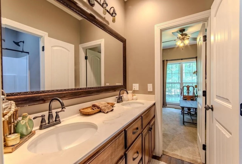 Bathroom featuring a double vanity with white oval sinks, dark bronze faucets, and a large framed mirror with integrated lighting