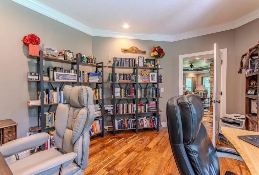 Dedicated room featuring wood-finish flooring, crown molding, recessed lighting, and built-in shelving