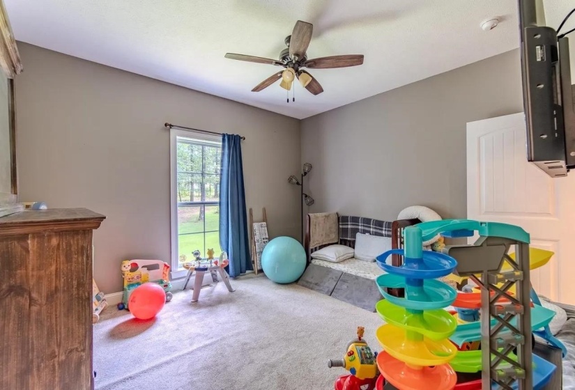Room featuring a vaulted ceiling with a ceiling fan, a window with exterior views, and neutral carpet flooring