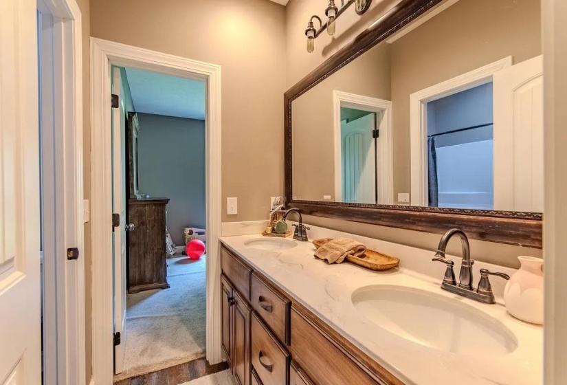 Bathroom featuring a double vanity with stone-finish countertops, dual undermount sinks, and bronze-finish fixtures