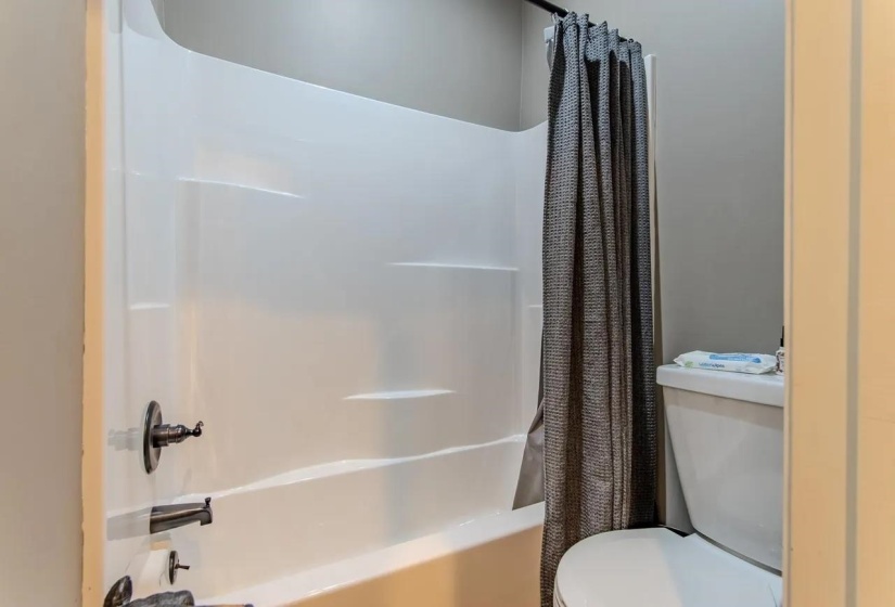 White fiberglass tub and shower combination with oil-rubbed bronze fixtures