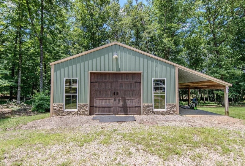 Metal pole barn structure featuring a sage green exterior with stone veneer accents