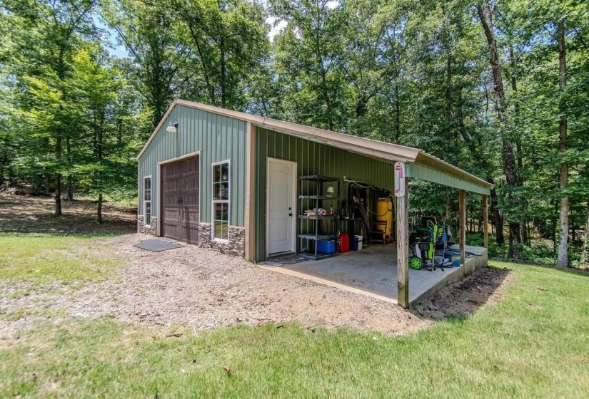 Metal outbuilding featuring a covered porch, an overhead door, and an entry door