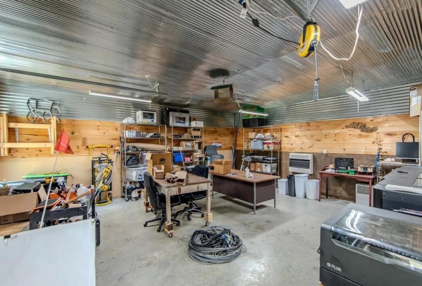 Utility space featuring corrugated metal ceiling, wood-paneled walls, concrete flooring, and fluorescent lighting